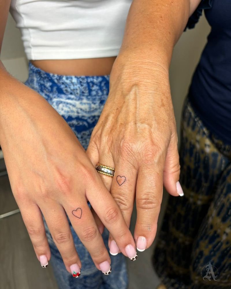 Tatuaje de corazones diminutos a juego en los dedos, fine line en negro y gris