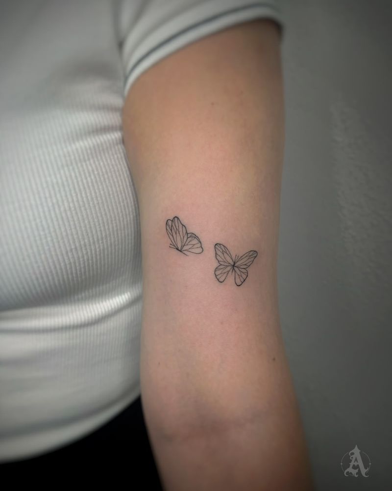 Tatuaje de mariposas en vuelo en el tríceps, fine line en negro y gris