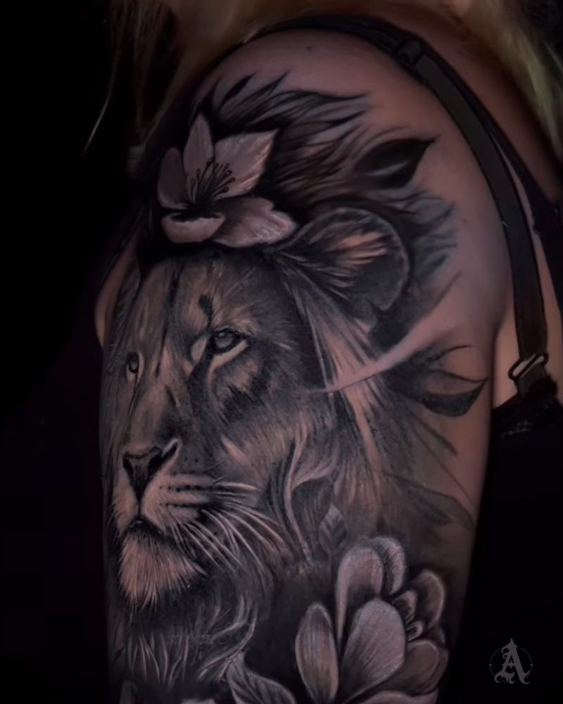 Tatuaje realista de un león rodeado de magnolias en el hombro, en negro y gris
