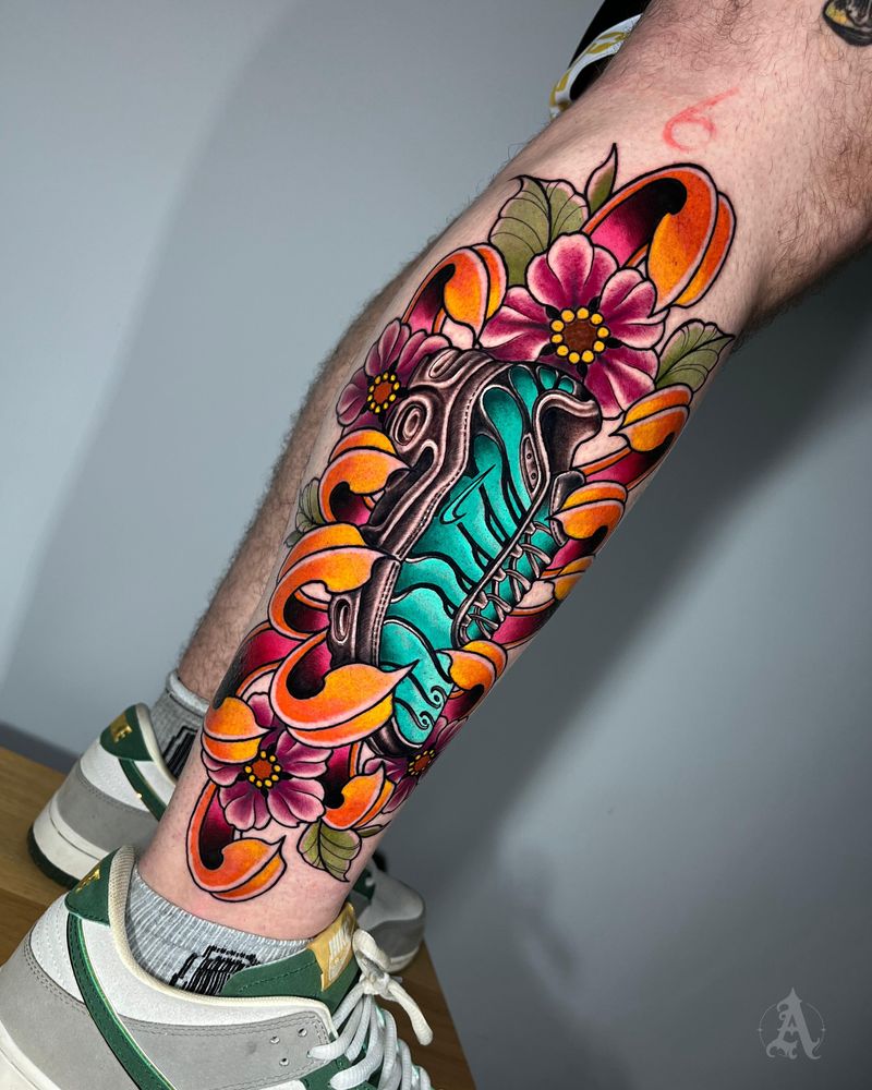 Tatuaje de flores y hoja en espinilla, neo-tradicional con color